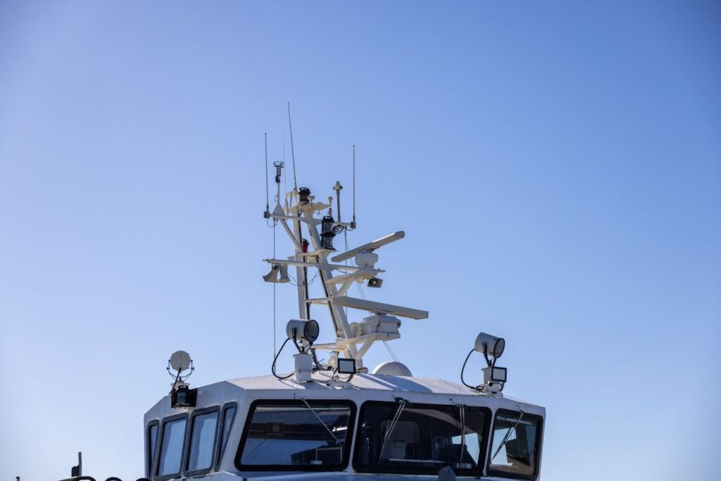 Marine vessel bridge topped with antennas, lights, and radar equipment