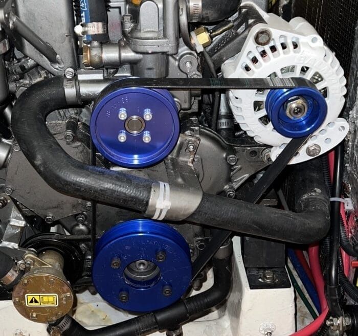Close-up of a marine engine with alternator, pulleys, and drive belts